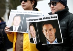 FILE - People hold signs calling for China to release Canadian detainees Michael Spavor and Michael Kovrig, in Vancouver, British Columbia, Canada, March 6, 2019.