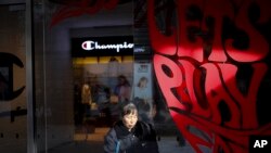 A cleaner wipes window panels near a shop of American sportswear brand Champion, at the capital city's popular shopping mall in Beijing, Feb. 13, 2019.