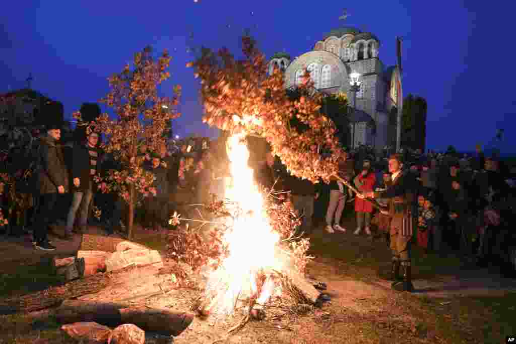 Christian Orthodox believers, who follow the Julian calendar and celebrate Christmas on Jan. 7, burn dried oak branches, the Yule log symbol for the Orthodox Christmas Eve, in front of St. Luke church in Belgrade, Serbia.