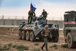 FILE - Russian troops with military vehicles are seen on patrol outside the town of Darbasiyah in Syria's northeastern Hasakeh province, on the border with Turkey, Nov. 1, 2019.