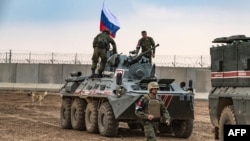 FILE - Russian troops with military vehicles are seen on patrol outside the town of Darbasiyah in Syria's northeastern Hasakeh province, on the border with Turkey, Nov. 1, 2019.