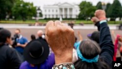 FILE - Wolf Ramerez of Houston, Texas, center, joins others with the Carrizo Comecrudo Tribe of Texas in holding up his fists as indigenous and environmental activists protest in front of the White House in Washington, Oct. 11, 2021.