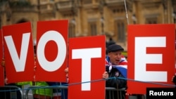 Anti-Brexit demonstrators hold placards outside the Houses of Parliament in London, Britain, Dec. 10, 2018.