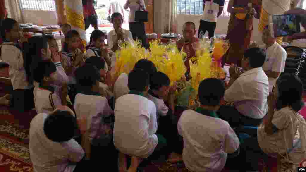 សិស្សានុសិស្សរបស់សាលាសេនត្រល់ផាកកម្ពុជា (Central Park of Cambodia) យកចង្ហាន់ និងបច្ច័យមួយចំនួនមកប្រគេនព្រះសង្ឃនៅវត្តសំពៅមាសក្នុងរាជធានីភ្នំពេញ នៅថ្ងៃកាន់បិណ្ឌទី៥ (ថ្ងៃទី២១ ខែកញ្ញា ឆ្នាំ២០១៦)។ (ប៊ុន ប៉េងហ៊ុយ/VOA)
