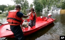 Susan Hedgepeth is assisted along with her dog Cooper by members of the U.S. Coast Guard in Lumberton, N.C., Sept. 16, 2018, following flooding from Hurricane Florence. Hedgepeth was moved to higher ground.