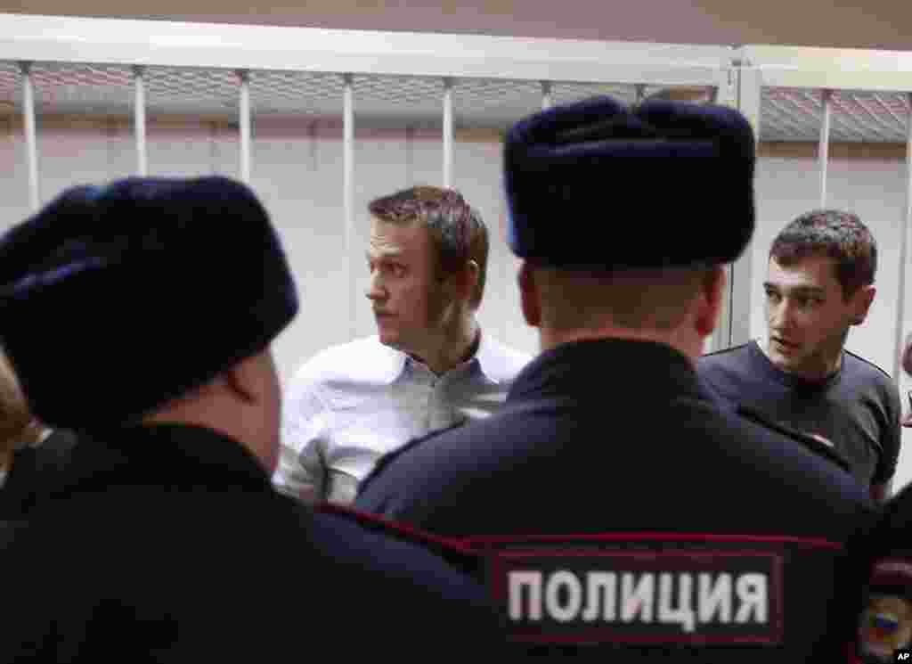 Russian opposition activist and anti-corruption crusader Alexei Navalny and his brother Oleg Navalny stand at the cage in court, in Moscow, Tuesday, Dec. 30, 2014.