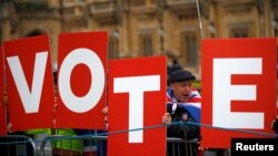 Anti-Brexit demonstrators hold placards outside the Houses of Parliament in London, Britain, Dec. 10, 2018.