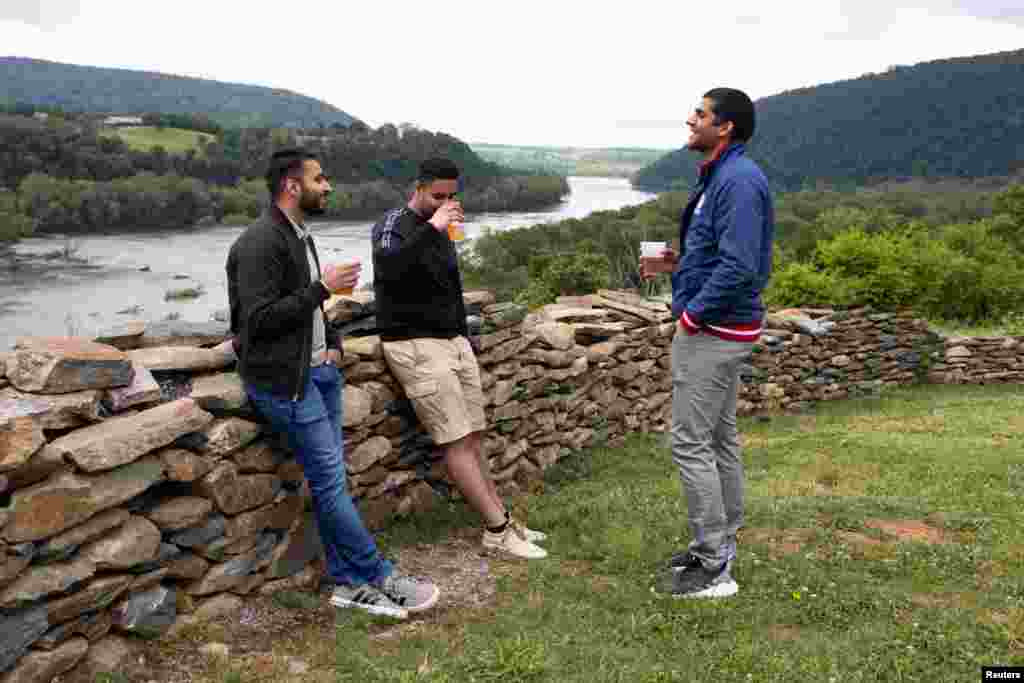 Tres j&#243;venes conversan mientras beben en un campamento en Harpers Ferry Adventure Center, en Hillsboro, Virginia.