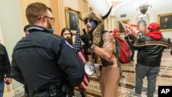 FILE - Supporters of President Donald Trump are confronted by U.S. Capitol Police officers outside the Senate Chamber inside the Capitol in Washington, Jan. 6, 2021. The Arizona man seen in the fur hat, Jacob Chansley, was taken into custody Jan. 9.