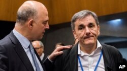 European Commissioner for Economy Pierre Moscovici, left, speaks with Greek Finance Minister Euclid Tsakalotos during a meeting of eurogroup finance ministers at the European Council building in Luxembourg, June 15, 2017.