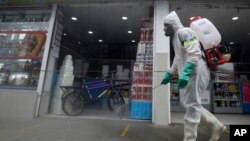 Un trabajador con equipo de protección completo en medio de la pandemia de coronavirus desinfecta una acera en Corabastos, uno de los centros de distribución de alimentos más grandes de América Latina, en Bogotá, Colombia. Junio, 23 2020. 