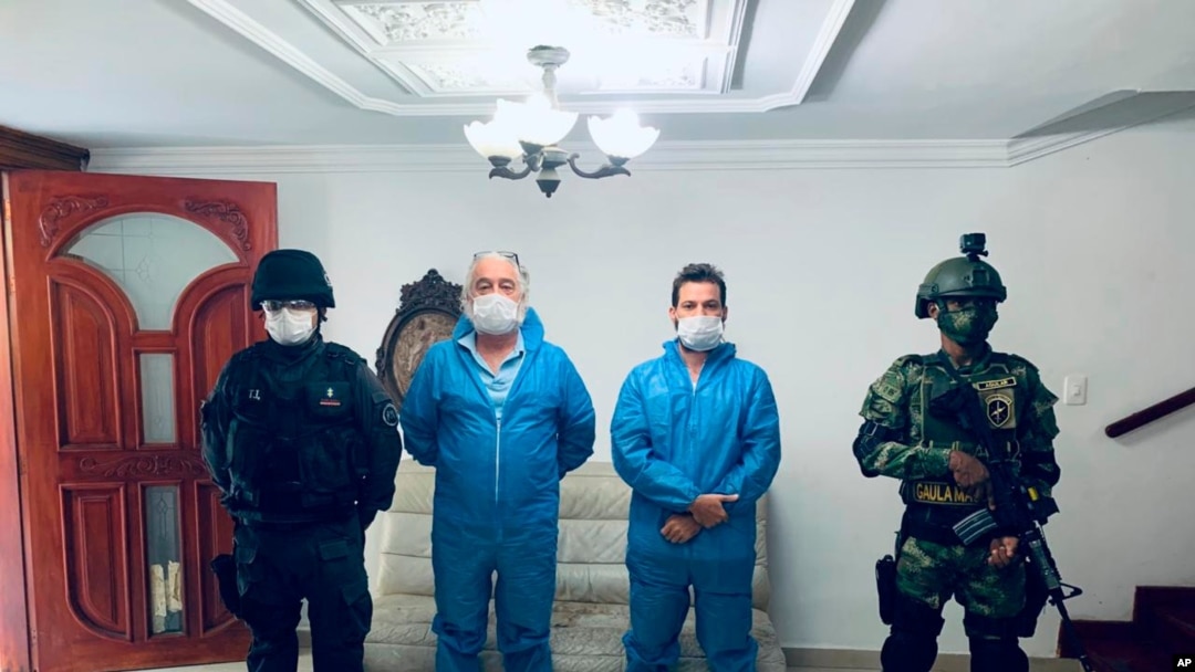 In this photo released by Colombia's Prosecutor's Press Office, a police officer and a soldier flank Mark Grennon, second left, and his son Joseph Grennon during a raid in Santa Marta, Colombia, Aug. 11, 2020.