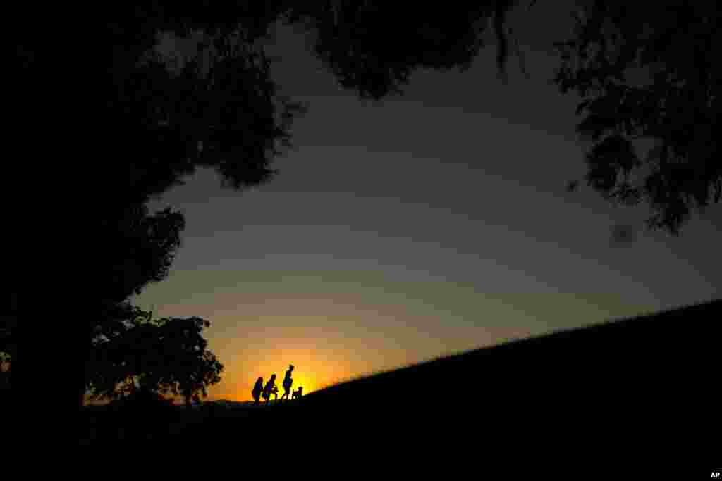 Warga berjalan di puncak bukit menikmati suasana matahari terbenam di taman kota Tio Pio di Madrid, Spanyol.