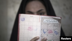 A woman holds her identification in front of her face after voting at a polling station during Iran's parliamentary election in southern Tehran, March 2, 2012.