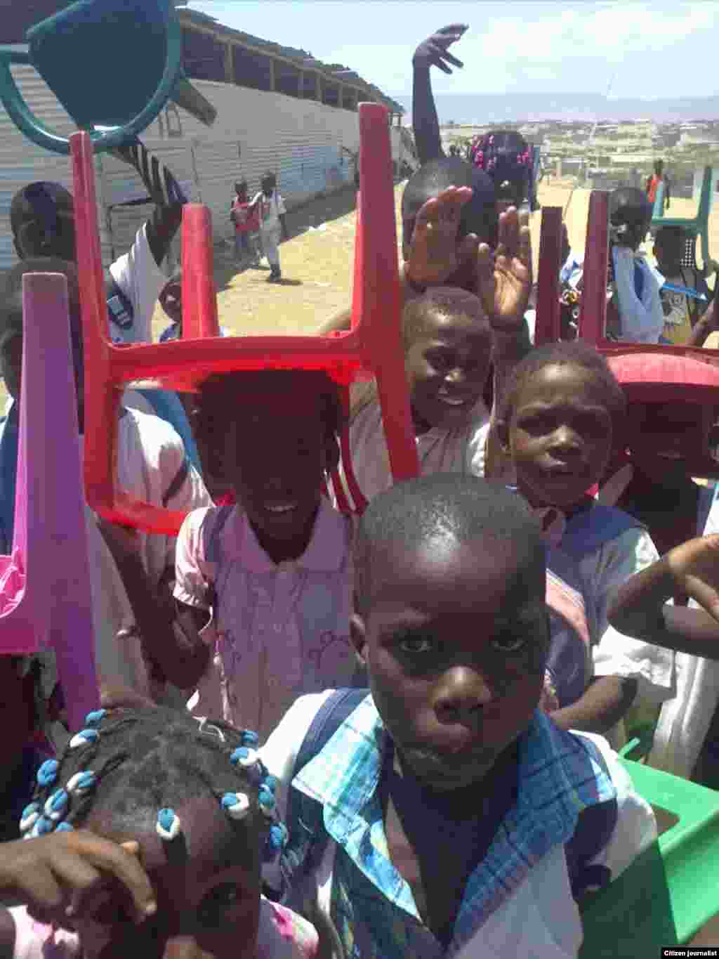 Meninos curiosos fixam a câmara fotográfica. Ao fundo uma das salas de chapa. O olhar de um ouvinte da VOA pelo Ensino Primário, Escola 4, província de Benguela, Angola. Março 2014