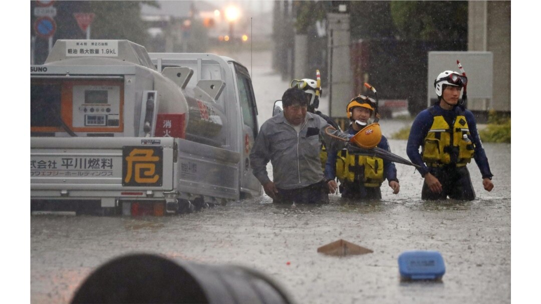 Seorang pria diselamatkan oleh polisi saat mobilnya terjebak di jalanan yang banjir yang dipicu oleh hujan lebat di Omuta, prefektur Fukuoka, Jepang selatan 7 Juli 2020 dalam foto yang diambil oleh Kyodo, Jepang. (Foto: Kyodo / via REUTERS)