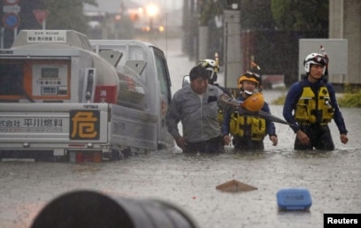 Seorang pria diselamatkan oleh polisi saat mobilnya terjebak di jalanan yang banjir yang dipicu oleh hujan lebat di Omuta, prefektur Fukuoka, Jepang selatan 7 Juli 2020 dalam foto yang diambil oleh Kyodo, Jepang. (Foto: Kyodo / via REUTERS)