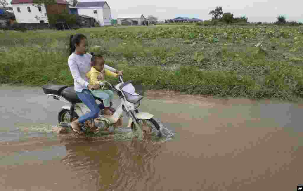 موتورسواری دو خواهر در جاده ها و مسیرهای آب گرفته ناشی از وقوع سیل در کامبوج