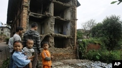 Nepalese children and other people stand near the debris of collapsed buildings damaged by an earthquake that shook northeastern India on Sunday night, in Katmandu, Nepal, Sept. 19, 2011.