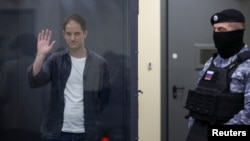 Nhà báo Evan Gershkovich của Wall Street Journal, người đang bị giam giữ vì tội gián điệp, vẫy tay sau bức tường kính dành cho các bị cáo khi tham dự phiên tòa ở Moscow, Nga, ngày 23/4/2024.