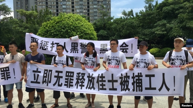 2018年8月6日,人们在中国广东省深圳市坪山区燕子岭派出所外示威,手持标语,支持佳士工厂工人组建工会要求。