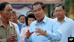 FILE - Cambodian Prime Minister Hun Sen, center, of ruling Cambodian People's Party speaks after voting in the senate election at Takhmau polling station in Kandal province, southeast of Phnom Penh, Cambodia, Feb. 25, 2018.