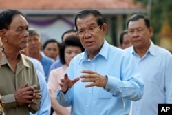 FILE - Cambodian Prime Minister Hun Sen, center, of ruling Cambodian People's Party, speaks after voting in the Senate election at Takhmau polling station in Kandal province, southeast of Phnom Penh, Cambodia, Feb. 25, 2018.