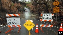 A road is closed because of flooding in an area burned by the Woolsey Fire in Malibu, Calif., Dec. 6, 2018. A second fall storm dumped snow and rain that jammed traffic on Southern California highways and loosened hillsides in wildfire burn areas.