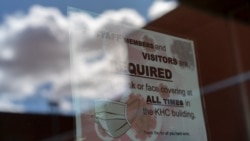 FILE - In this April 18, 2020, file photo, a sign on a door warns people to wear face coverings at the Kayenta Health Center on the Navajo reservation in Kayenta, Arizona.