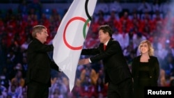 在索契冬奧會閉幕式上，國際奧委會主席巴赫把奧林匹克旗幟交給南韓平昌市市長李熙來。 （2014年2月23日）