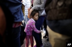 In this June 13, 2018 photo, Nicole Hernandez, of the Mexican state of Guerrero, holds on to her mother as they wait with other families to request political asylum in the United States, across the border in Tijuana, Mexico.