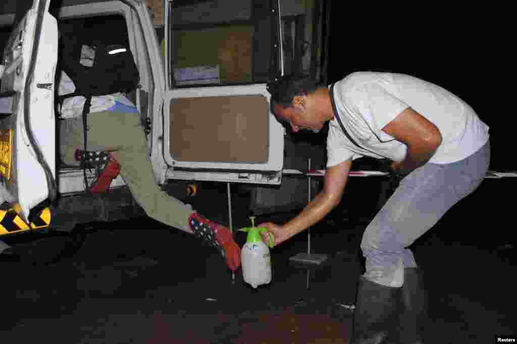 Seorang pekerja untuk LSM internasional Dokter Tanpa Batas menyemprot sepatu bot koleganya dengan disinfektan klorin untuk mencegah Ebola di Monrovia, Liberia (20/10).&nbsp;(Reuters/James Giahyue) 