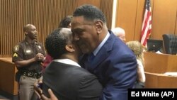 Richard Phillips, right, hugs Det. Patricia Little in a courtroom on Wednesday, March 28, 2018, in Detroit, Michigan. Phillips, a Michigan man whose murder conviction was thrown out after he spent 45 years in prison will not face a second trial. (AP Photo/Ed White)