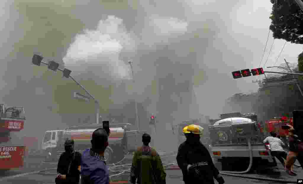 People, right, take cover as an explosion is heard during a fire that engulfs the Manila Pavilion Hotel and Casino in Manila, Philippines.