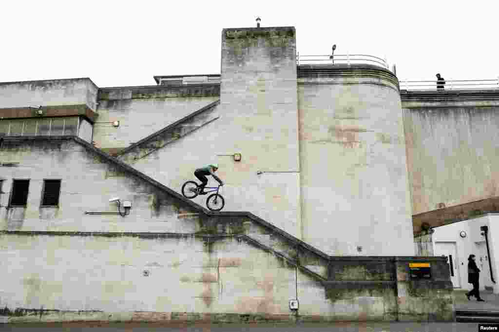 A cyclist steers down the narrow handrail of a stairway on Waterloo Bridge in London, April, 27, 2019.