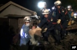 In this image made from video and provided by Kumamoto Prefectural Police, eight-month-old baby Miku Nishimura is carried away after being rescued from her home, which collapsed in a magnitude-6.5 earthquake in Mashiki town, Kumamoto prefecture, southern Japan, early Friday, April 15, 2016.