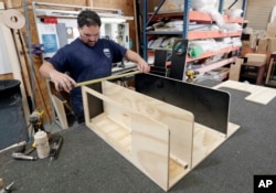 In this July 11, 2018, photo, a worker assembles interior boat cabinets in Orlando, Florida, which has no state income tax.