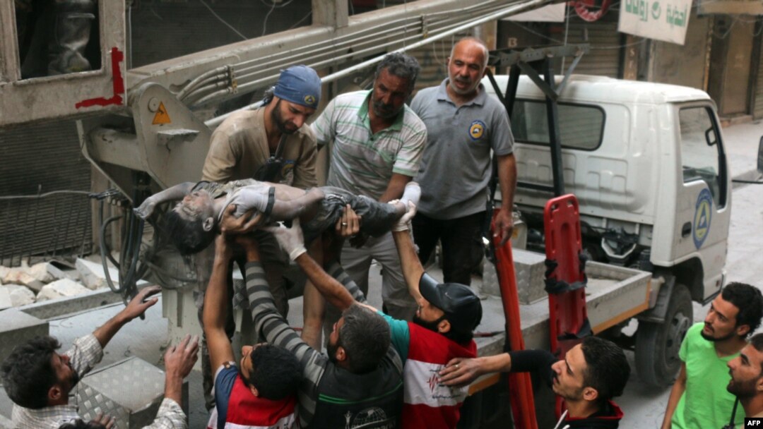 Syrian civil defense volunteers, known as the White Helmets, pass the body of a boy after he was pulled from the rubble following a government forces airstrike on the rebel-held al-Shaer neighborhood of Aleppo, Sept. 27, 2016.