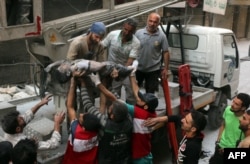 Syrian civil defense volunteers, known as the White Helmets, pass the body of a boy after he was pulled from the rubble following a government forces air strike on the rebel-held al-Shaer neighborhood of the northern city of Aleppo, Sept. 27, 2016