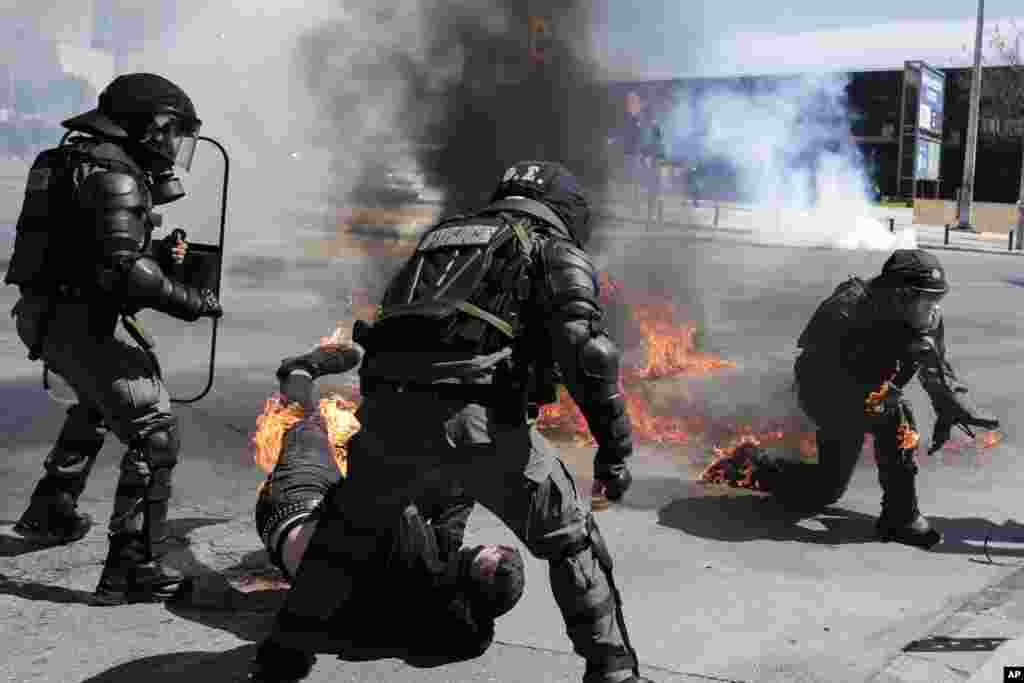 A protester, bottom, and riot policeman react after catching fire from a gasoline bomb during a protest in the the northern city of Thessaloniki, Greece.