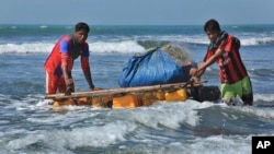 Rohingya fishermen pull their raft made of empty plastic containers along the coastline of the Bay of Bengal in Tha Pyay Taw village, Maungdaw, western Rakhine state, Myanmar, Jan. 16, 2017.. 