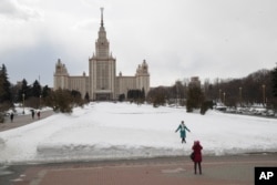 A tourist takes a picture in the area where a 25,000-capacity fan zone of the Russia Soccer World Cup 2018 will be placed, with Moscow State University's main building in the background, in Moscow, Russia, March 28, 2018.