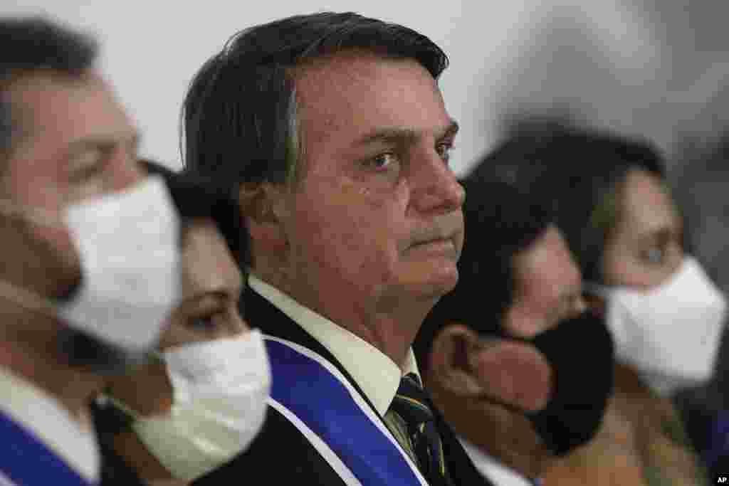 Brazil's President Jair Bolsonaro listens to his nation's anthem during a ceremony marking Diplomat Day at Itamaraty Palace in Brasilia, Brazil, Thursday, Oct. 22, 2020, amid the COVID-19 pandemic. (AP Photo/Eraldo Peres)