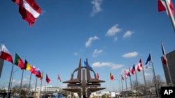 （资料照片）北大西洋公约组织布鲁塞尔总部外，北约的象征雕塑和成员国的旗帜。