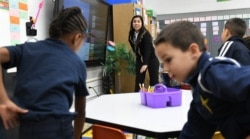 Teaching assistant Dilia Samadova warms up--both figuratively and literally--Mrs. Zenobi's kindergarten class for a math lesson with a count to 100 at Our Lady of Peace School, Dec.11, 2019.