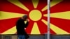 ARHIVA - Stanovnik Skoplja prolazi pored zastave Severne Makedonije (Foto: AP/Boris Grdanoski)