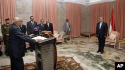 Yemen's newly appointed Prime Minister Mohammed Salem Basindwa (front L) takes the oath of office in front of Vice President Abd-Rabbu Mansour Hadi (R) at the Republican Palace in Sana'a, December 10, 2011.