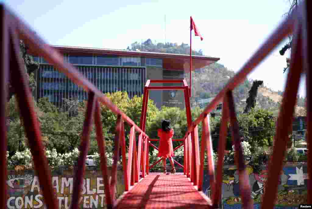 A woman stands at an urban intervention by Chilean artist Ivan Navarro called &quot;Rio de sangre&quot; (Blood river), a tribute to the coronavirus victims and in memory of the people thrown into the river during the Chilean dictatorship, in Santiago, Chile.