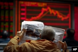 A man reads a newspaper reporting a story of U.S. President Donald Trump opening conditional dialogue with North Korean leader Kim Jong Un, at a brokerage house in Beijing, Jan. 8, 2017. Trade between China and North Korea fell 50 percent in December.