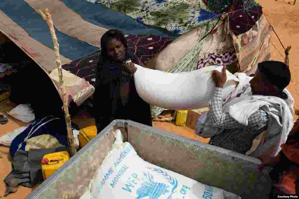 A recently arrived refugee from Mali is helped to load her rations of rice, oil and sugar onto a pick-up at the M'Berra refugee camp for Malian refugees in southeastern Mauritania, March 2, 2013. (Nyani Quarmyne/MSF)